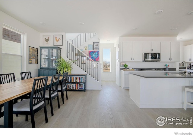 dining area with light wood finished floors, stairway, and baseboards