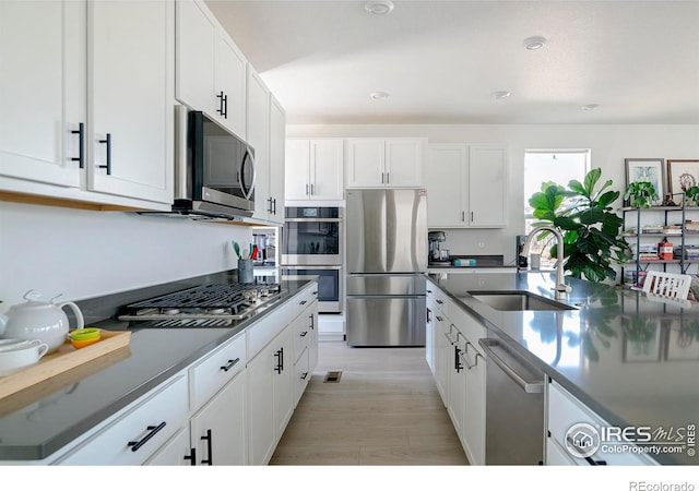 kitchen with white cabinets, light wood-style floors, appliances with stainless steel finishes, and a sink