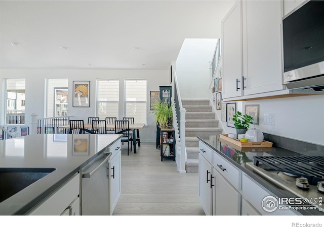 kitchen featuring white cabinetry, dark countertops, light wood-style floors, and appliances with stainless steel finishes