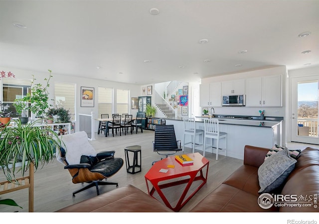 living area with stairs, recessed lighting, and light wood finished floors