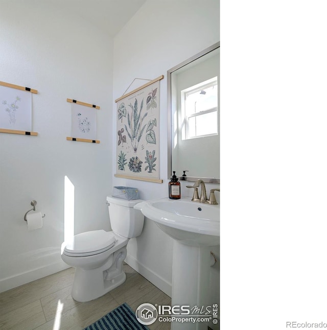 half bath with a sink, baseboards, and toilet