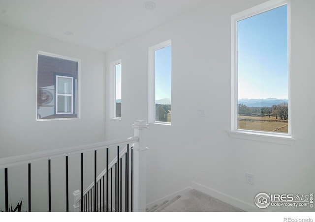 corridor featuring a mountain view, an upstairs landing, baseboards, and carpet flooring