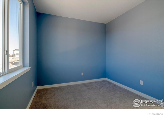 carpeted spare room featuring baseboards