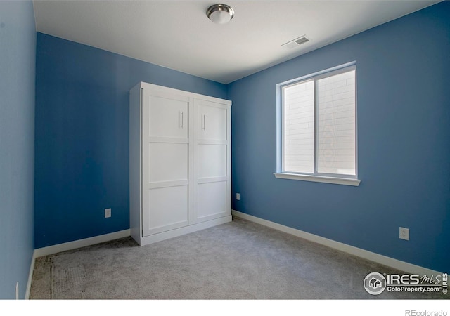 unfurnished bedroom with a closet, visible vents, baseboards, and carpet