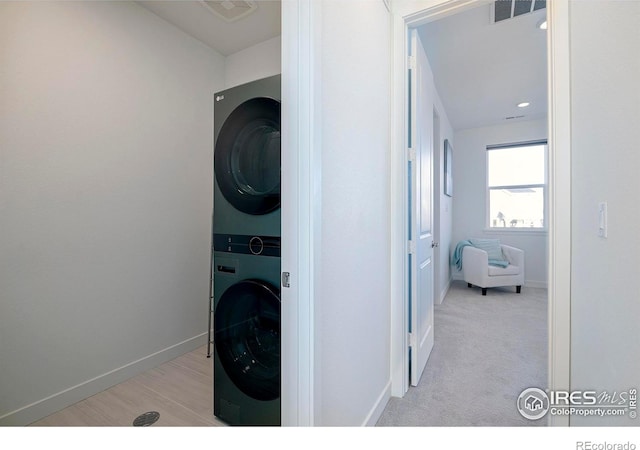 washroom featuring laundry area, visible vents, stacked washer and clothes dryer, and baseboards