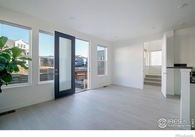 spare room featuring stairway, baseboards, visible vents, and light wood-type flooring