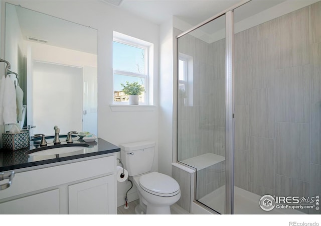 full bathroom featuring vanity, a shower stall, toilet, and visible vents