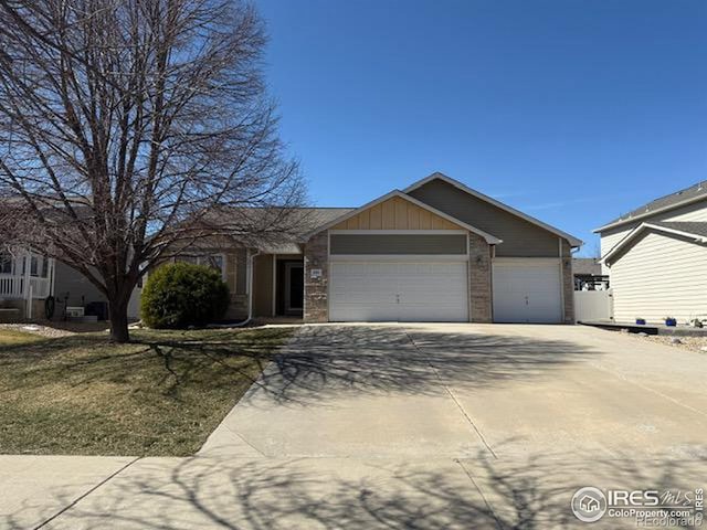 ranch-style home featuring brick siding, an attached garage, concrete driveway, and board and batten siding