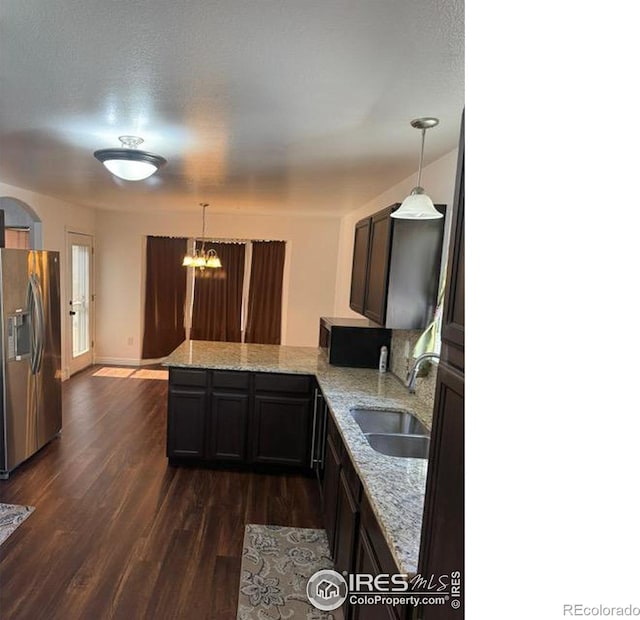 kitchen featuring dark wood-type flooring, a sink, light stone counters, a peninsula, and stainless steel fridge with ice dispenser