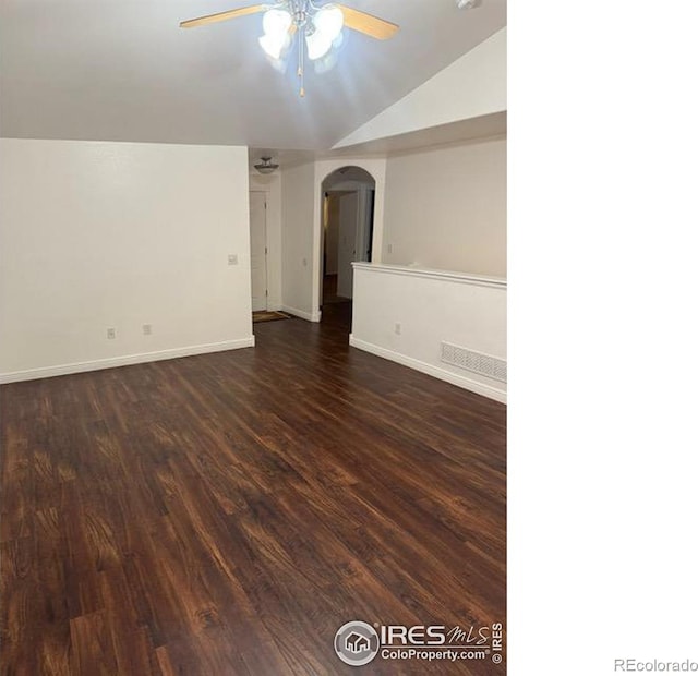 empty room with lofted ceiling, dark wood finished floors, arched walkways, baseboards, and ceiling fan