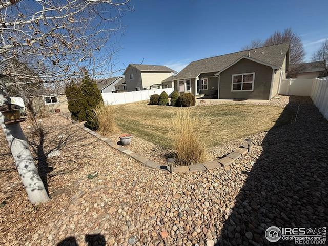 rear view of property with a yard and a fenced backyard