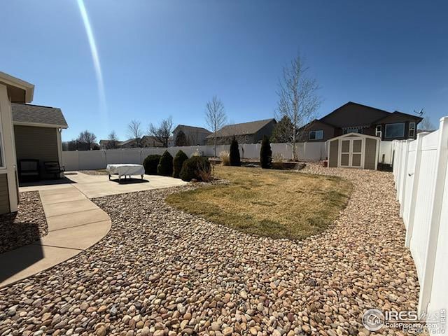 view of yard featuring a storage unit, a patio, an outdoor structure, and a fenced backyard