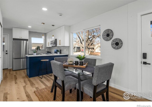 dining room featuring a wealth of natural light, light wood-type flooring, baseboards, and recessed lighting