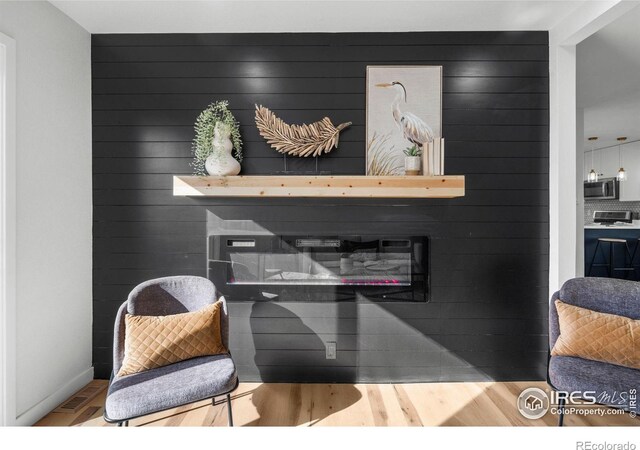 interior space with a glass covered fireplace, stainless steel microwave, stove, and wood finished floors