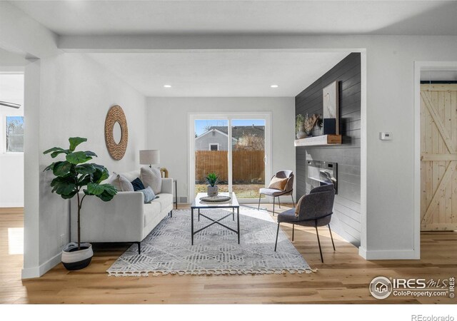 living area featuring recessed lighting, a large fireplace, baseboards, and wood finished floors