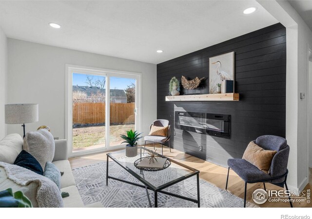 living room with recessed lighting, wood finished floors, an accent wall, and wood walls