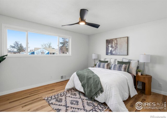 bedroom featuring visible vents, baseboards, wood finished floors, and a ceiling fan