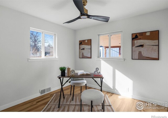 home office featuring wood finished floors, a healthy amount of sunlight, visible vents, and baseboards