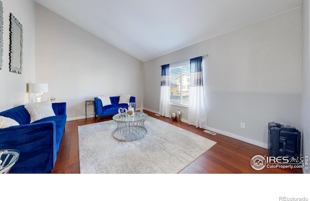 living room featuring lofted ceiling, wood finished floors, baseboards, and visible vents