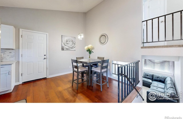 dining space with a high ceiling, wood finished floors, and baseboards