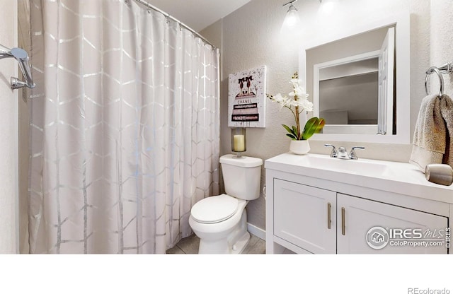 full bath with curtained shower, toilet, vanity, and a textured wall