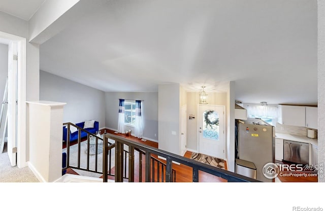 hallway featuring an upstairs landing, carpet flooring, and baseboards