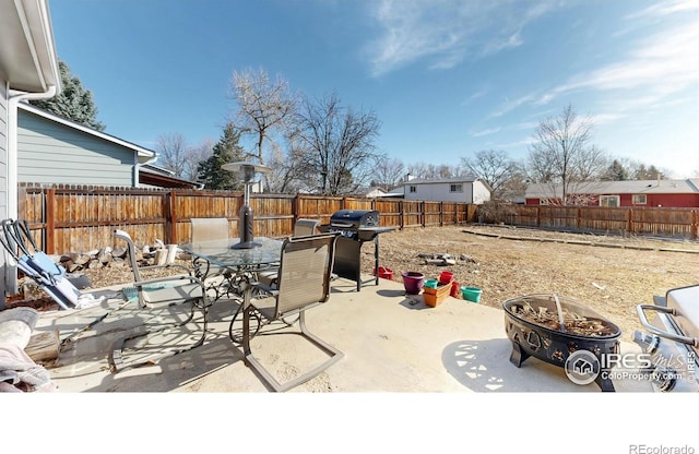 view of patio / terrace with grilling area, a fenced backyard, outdoor dining space, and an outdoor fire pit