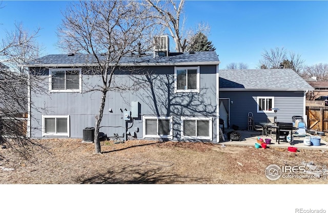 rear view of property featuring a patio area, central AC, roof with shingles, and fence