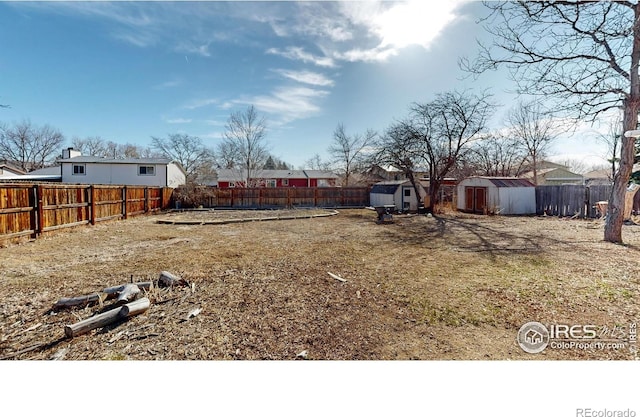 view of yard with an outbuilding, a fenced backyard, and a shed