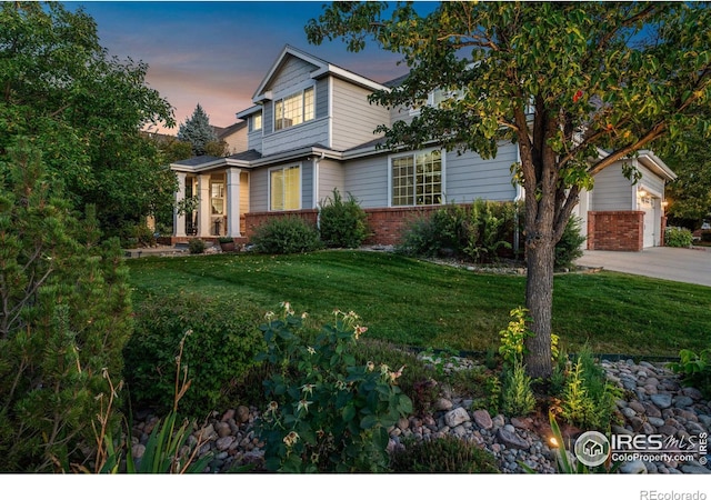 view of front of home with a front yard, concrete driveway, brick siding, and an attached garage