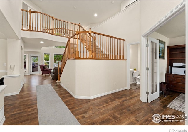 stairway featuring french doors, wood finished floors, recessed lighting, and a towering ceiling