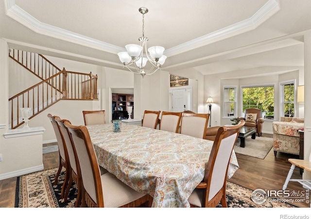 dining room featuring a tray ceiling, a notable chandelier, wood finished floors, and stairway