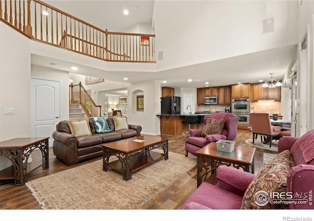 living room featuring baseboards, recessed lighting, dark wood-style flooring, stairs, and a towering ceiling