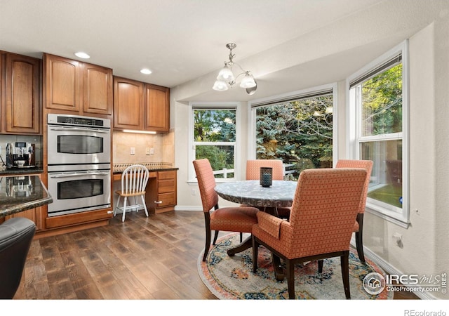 dining area with baseboards, plenty of natural light, an inviting chandelier, and dark wood-style floors