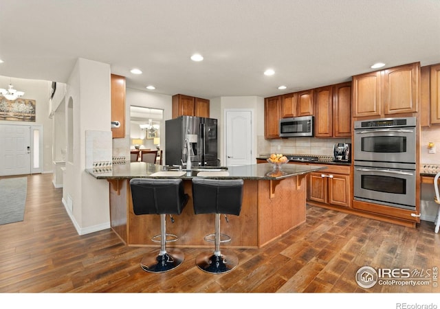 kitchen with a breakfast bar, backsplash, a notable chandelier, and appliances with stainless steel finishes