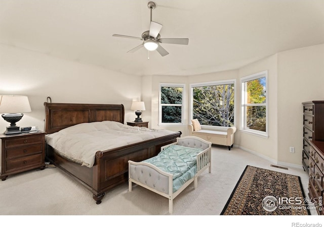 bedroom featuring visible vents, a ceiling fan, baseboards, and light carpet