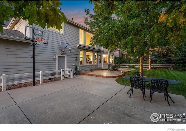 patio terrace at dusk featuring outdoor dining space and fence