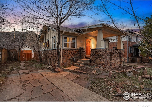 view of front of home featuring fence and stone siding