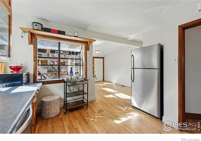 kitchen with light wood finished floors, glass insert cabinets, and freestanding refrigerator