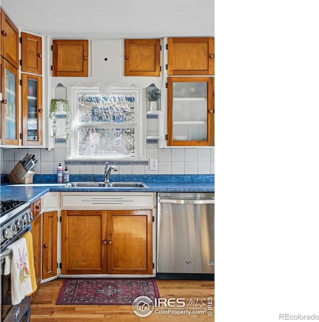 kitchen featuring brown cabinetry, decorative backsplash, appliances with stainless steel finishes, and a sink