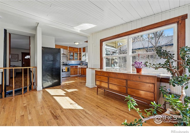 kitchen featuring a wealth of natural light, refrigerator, stainless steel stove, and brown cabinetry