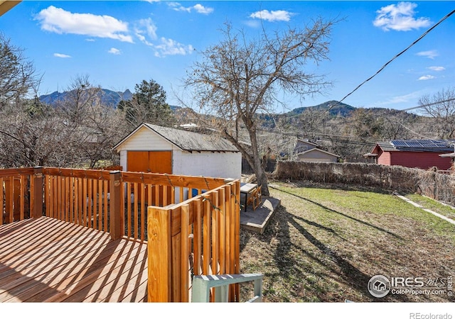 wooden deck with fence, a yard, an outbuilding, a mountain view, and a storage unit