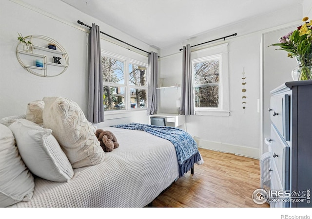 bedroom featuring multiple windows, wood finished floors, and baseboards