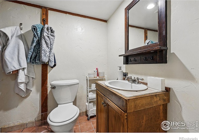 bathroom with vanity, toilet, a textured wall, and tile patterned flooring