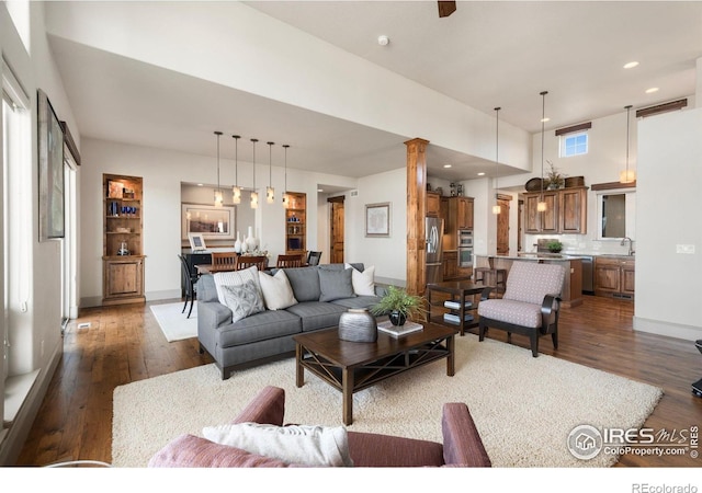 living area with dark wood finished floors, recessed lighting, and ornate columns