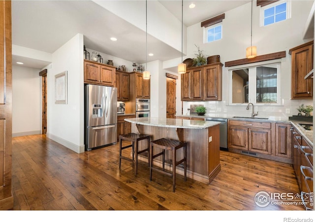 kitchen featuring appliances with stainless steel finishes, a kitchen island, dark wood-type flooring, and a sink