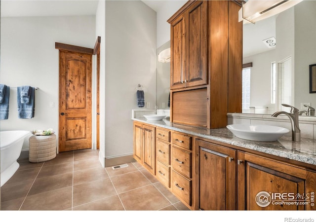 bathroom with tile patterned floors, a soaking tub, double vanity, and a sink