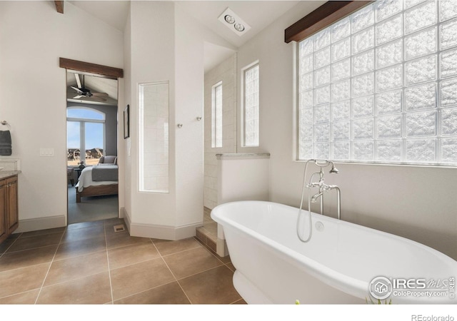 ensuite bathroom with tile patterned floors, ensuite bathroom, a freestanding bath, ceiling fan, and vaulted ceiling