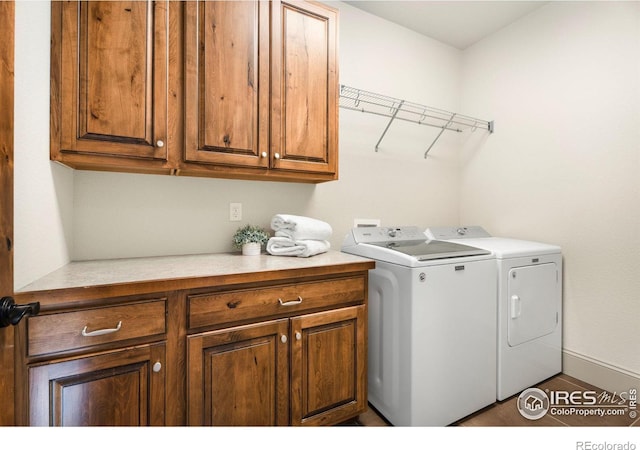 washroom featuring cabinet space, baseboards, and washer and clothes dryer