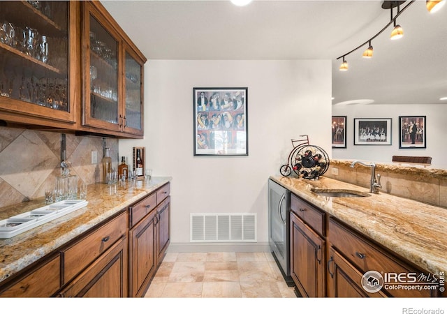 kitchen featuring tasteful backsplash, light stone countertops, visible vents, and a sink